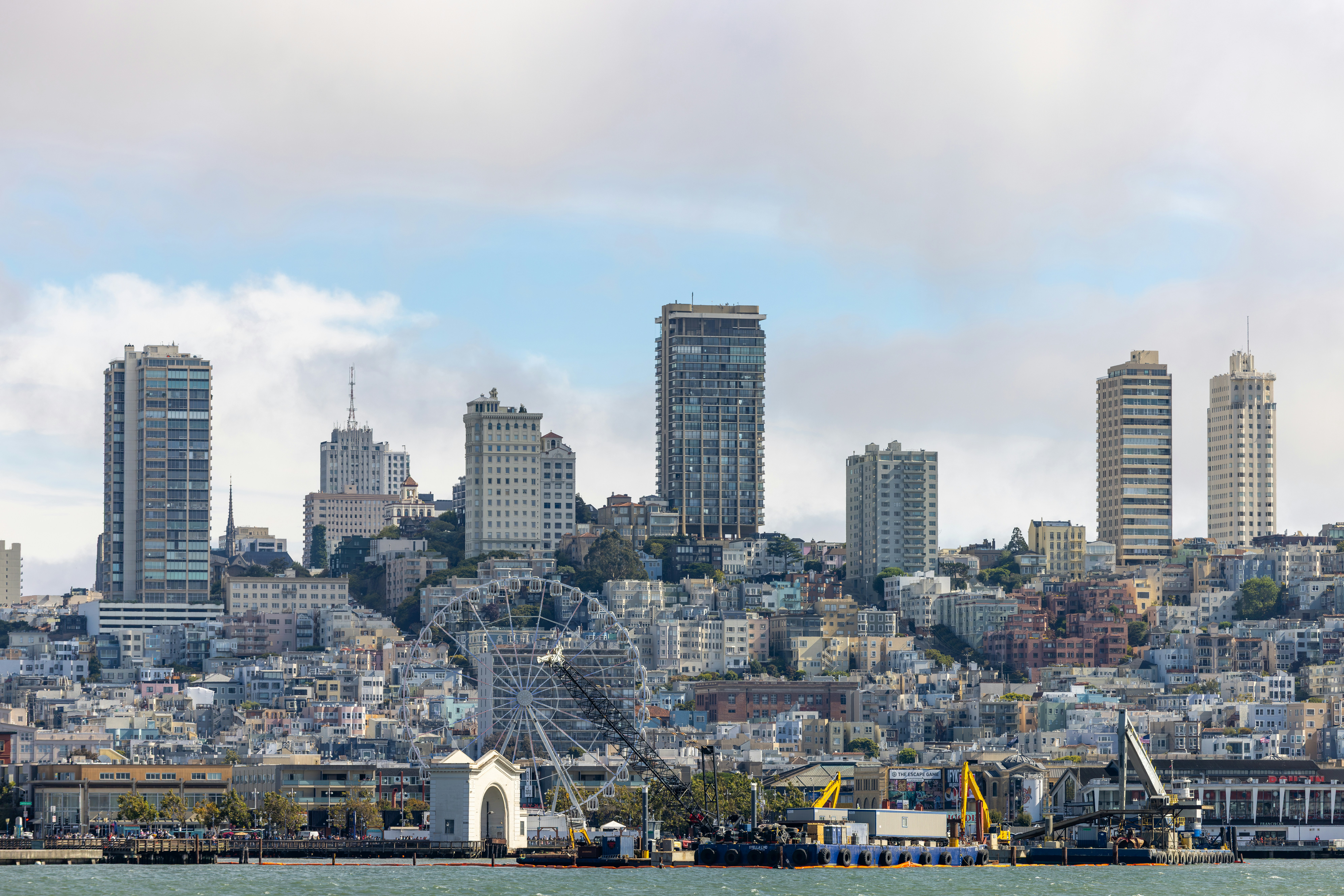 Cityscape with tall buildings and waterfront under a cloudy sky